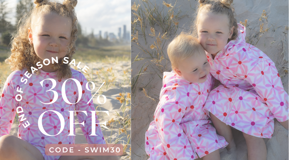girls sitting on the beach wearing their Zahli Swimmers and Hooded Beach Towel by Mae and Rae
