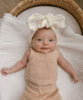 baby wearing a cute broderie topknot with gorgeous detail laying in basinet