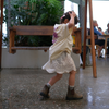 Toddler walking in the Butter Cosmic Tee and a lace skirt, showing the purple back print