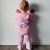 Toddler in the Dreamers Stardust Set: Baby Pink Dreamers Tee and pink tie-dye flares, showing the back print