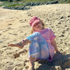 Girl sitting on the beach in the Dreamers Stardust Set: Baby Pink Dreamers Tee and blue tie-dye Stardust Flares