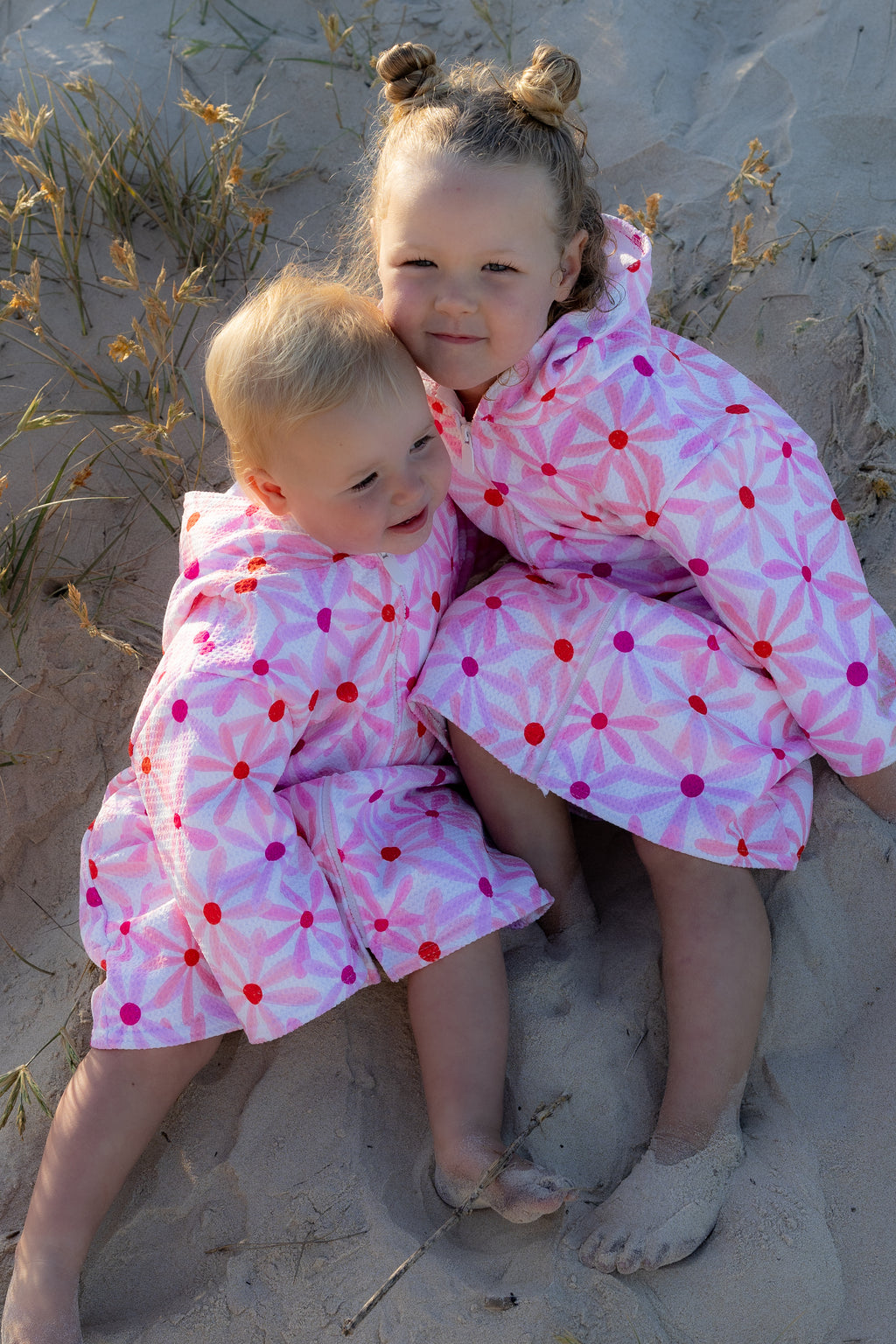 Kids cuddling wearing Mae and Rae Zahli hooded towel after swimming at the beach 