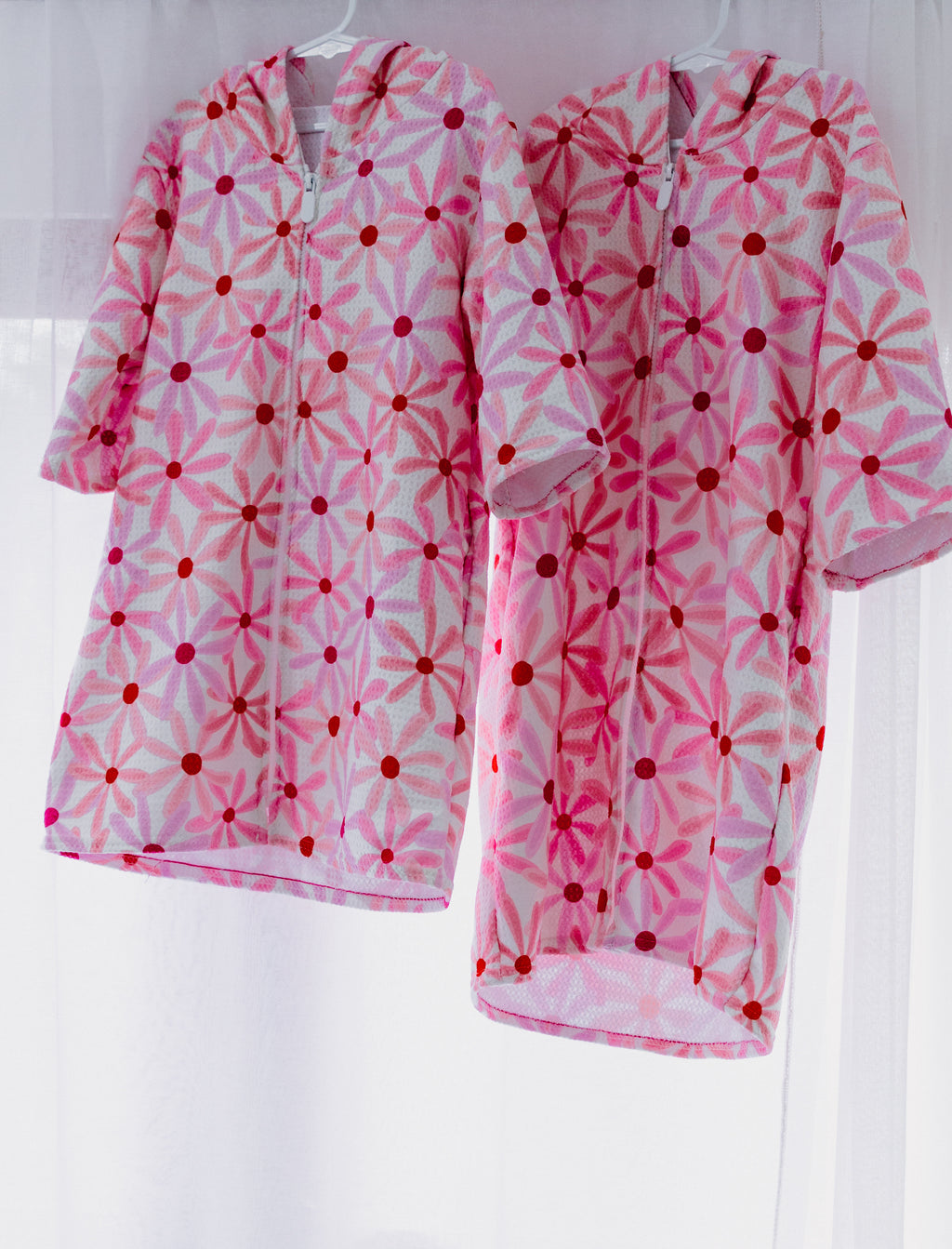 Mae and Rae Zahli hooded beach towel with floral pattern, hung in studio lighting