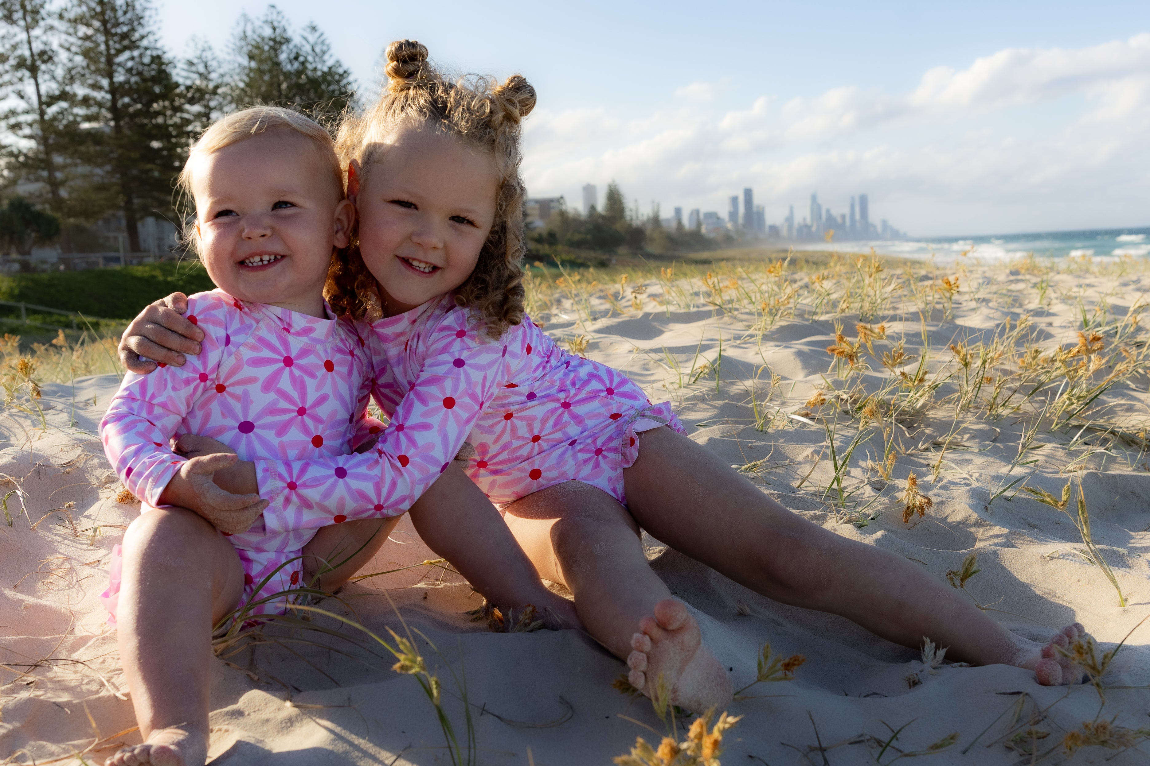 Kids cuddling at the beach wearing their new Mae and Rae Zahli swimmers